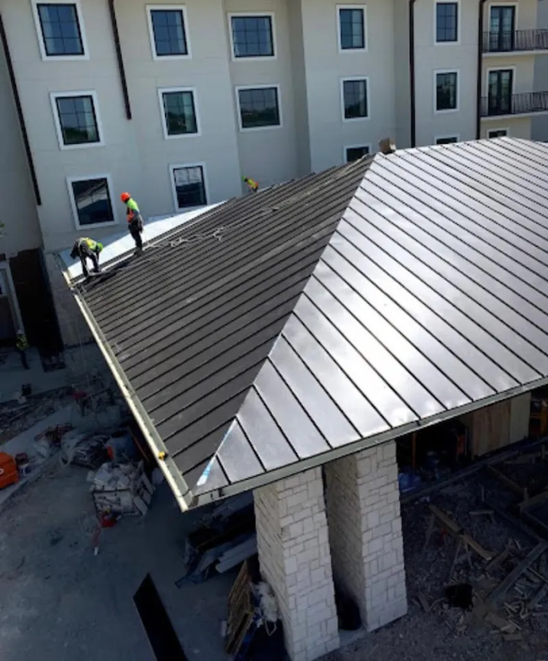 Crew installing standing seam metal roof panels on a commercial project in Trenton